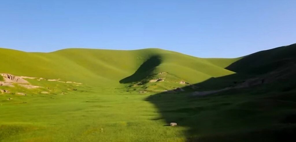نمایی از دشت چمتال ولایت فاریاب که زیبایی‌های طبیعی آن با چمنزارها و کوه‌های سبز به نمایش گذاشته شده است.